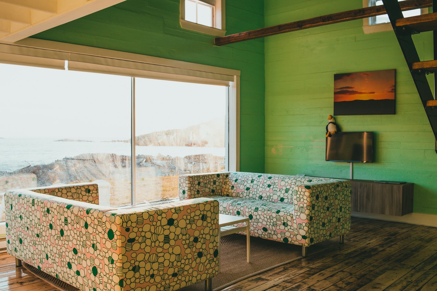 Two floral patterned sofas face a window overlooking the ocean.